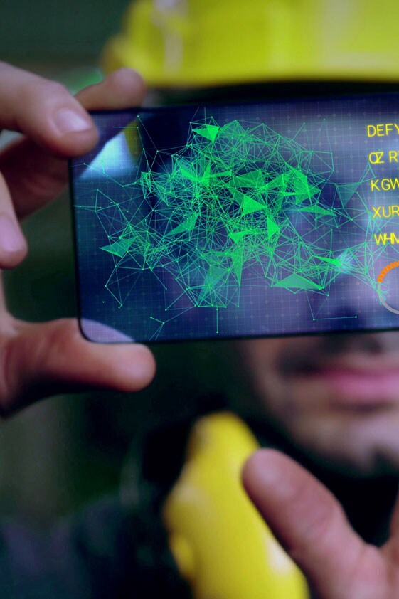 Image of man in yellow hat holding up phonescreen with connected data